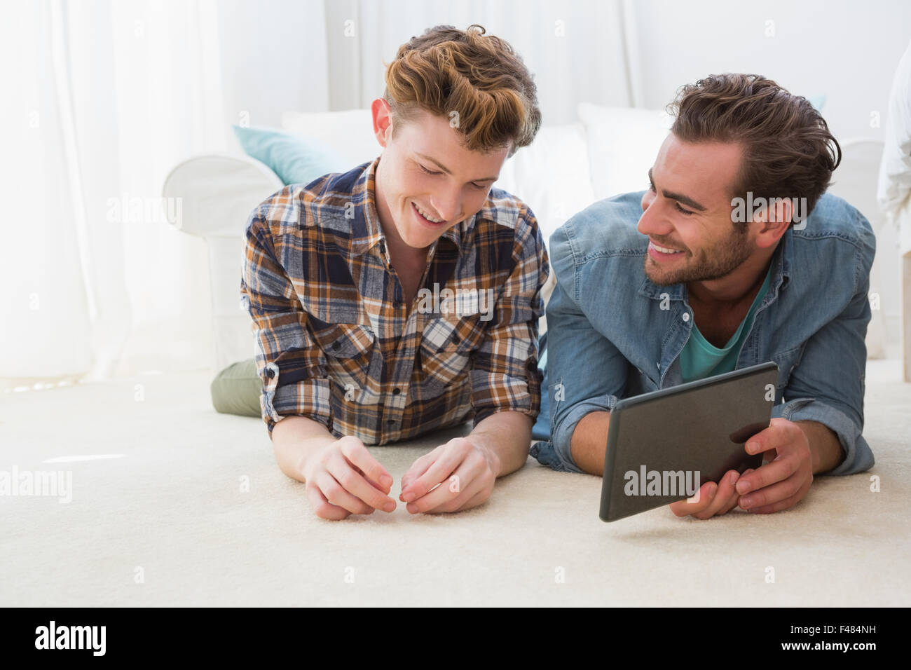 Froh, dass homosexuelle Paare am Boden liegend und mit tablet PC Stockfoto