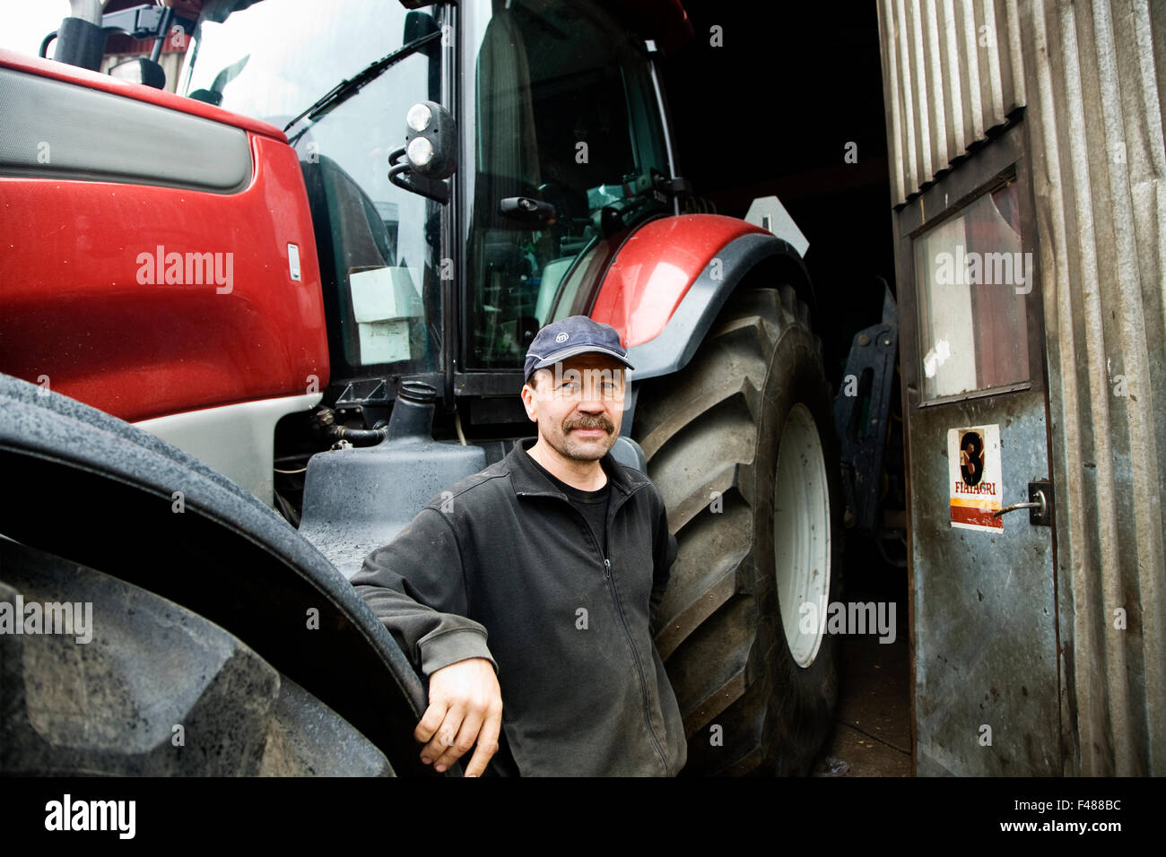 Porträt eines Bauern vor einem Traktor, Finnland. Stockfoto