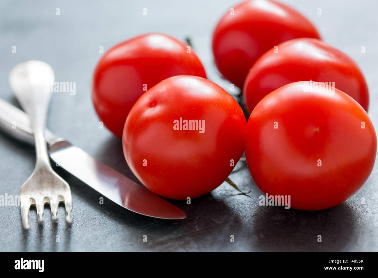 Reife Tomaten, Messer und Gabel. Stockfoto