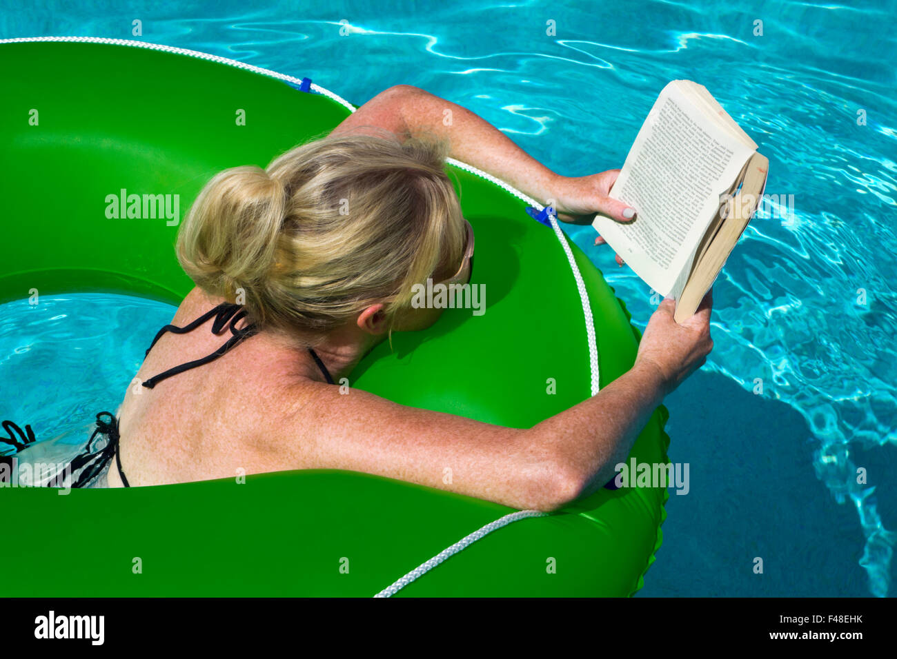 Frau liest in einem Pool im Urlaub Stockfoto