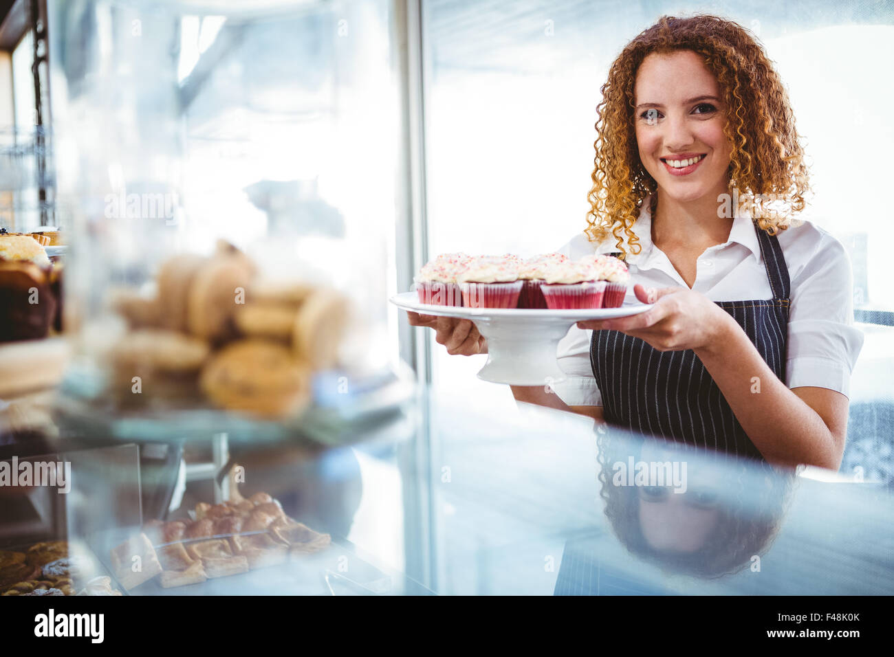 Hübsche Barista bereitet Platte mit cupcakes Stockfoto