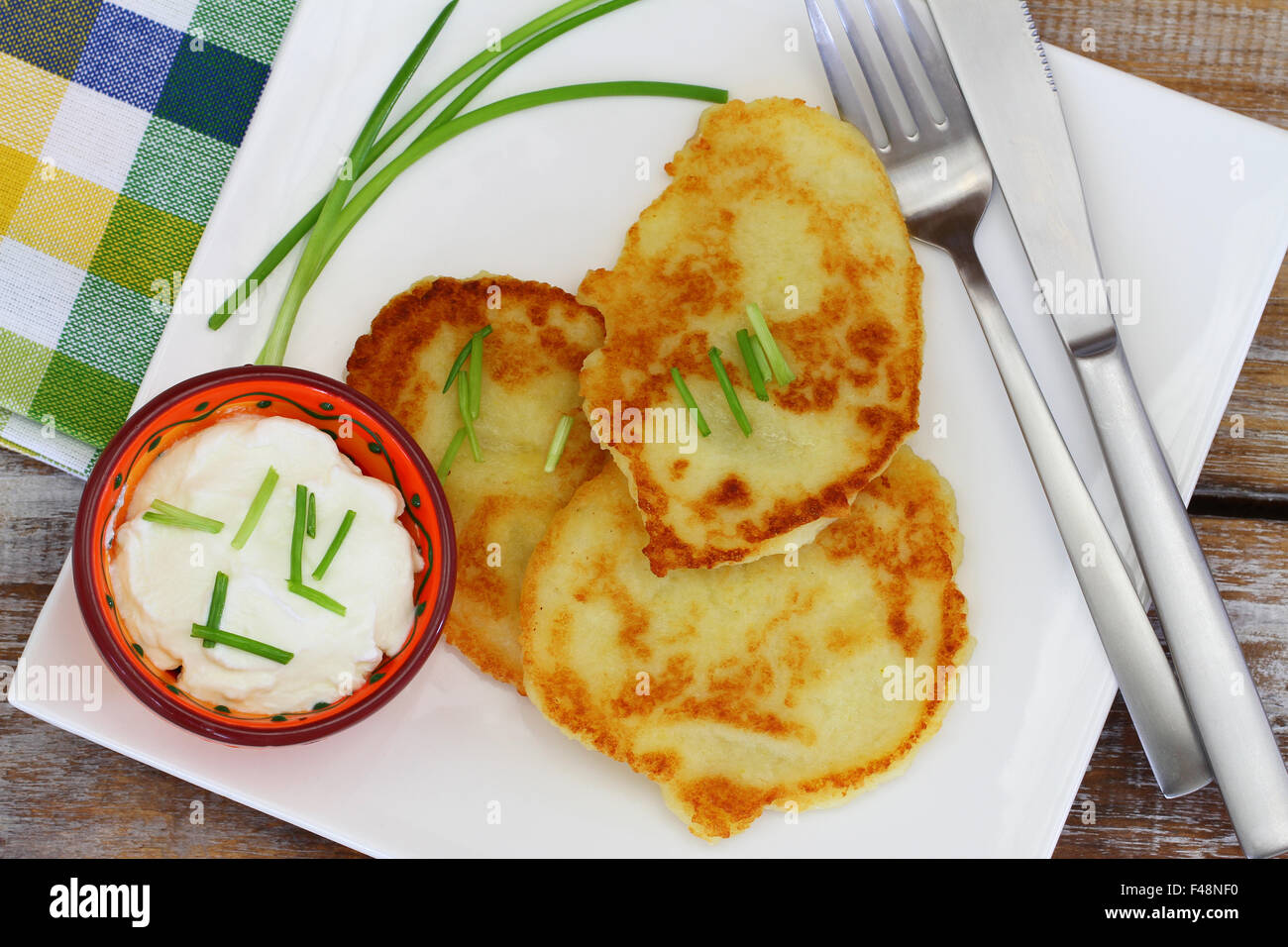 Kartoffel Krapfen auf weißen Teller mit Schüssel saure Sahne Stockfoto