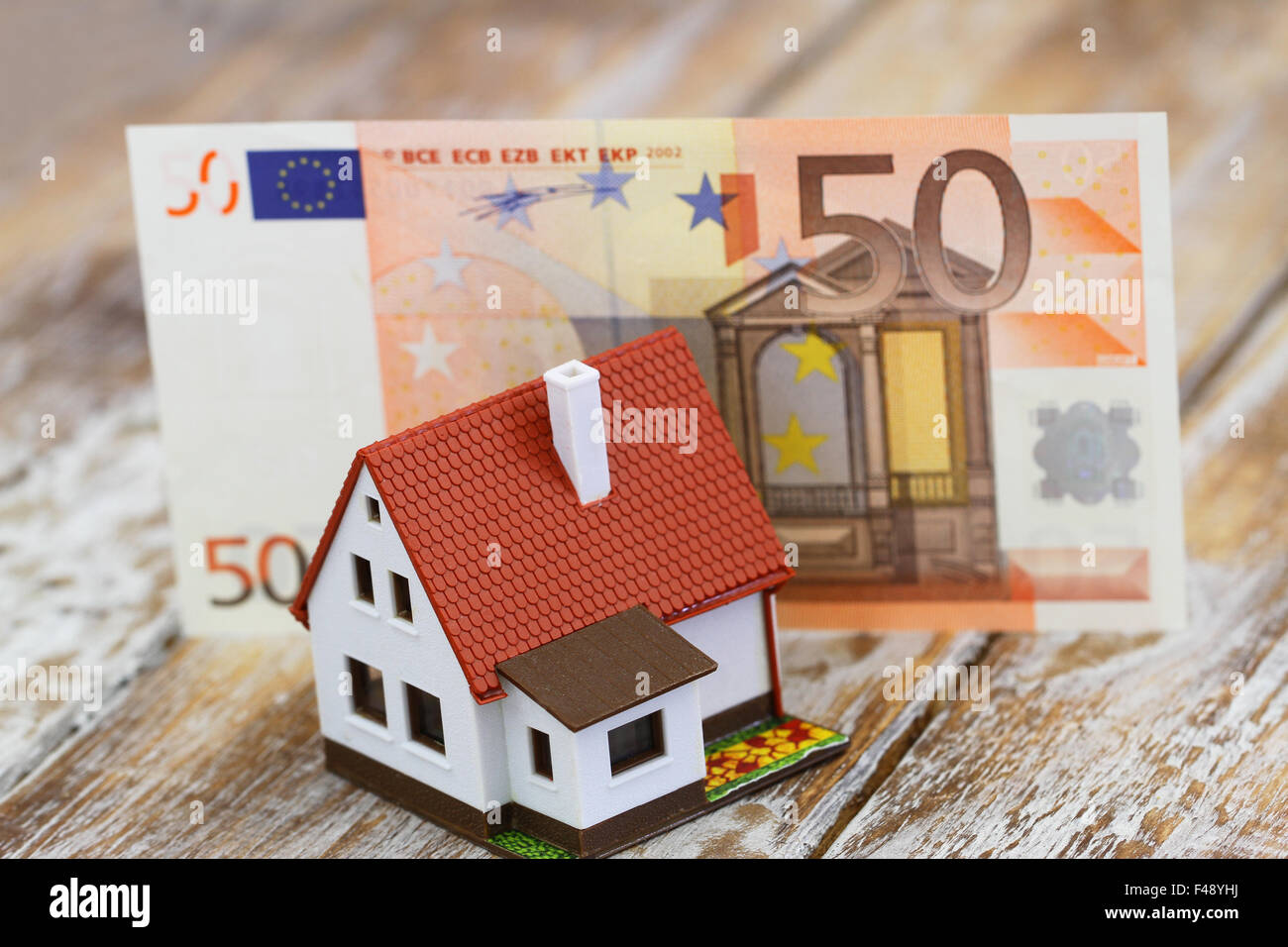 Musterhaus vor fünfzig Euro-Banknote auf rustikalen Holzoberfläche Stockfoto
