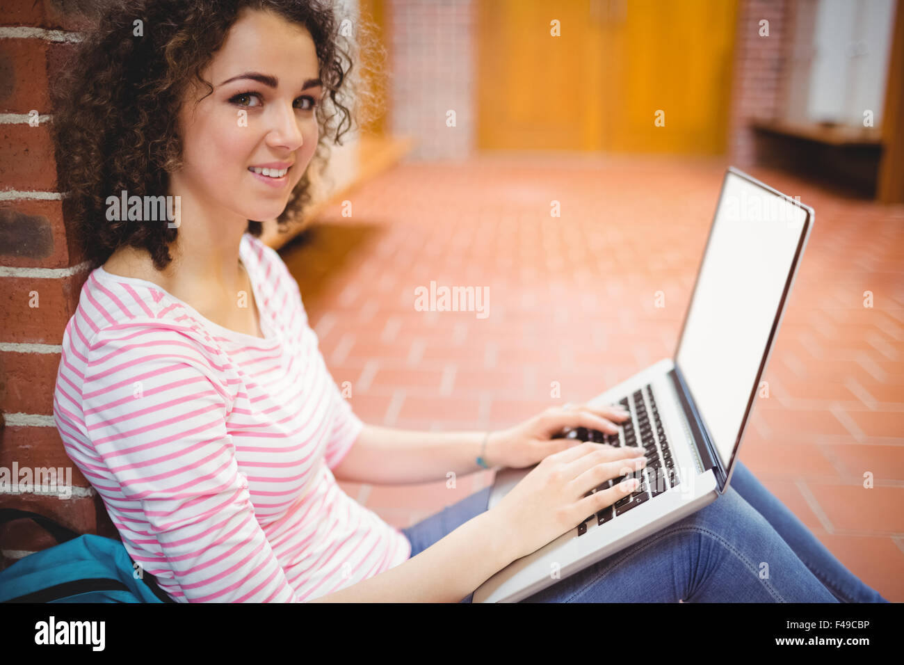 Hübsche Studentin mit ihrem Laptop im Flur Stockfoto