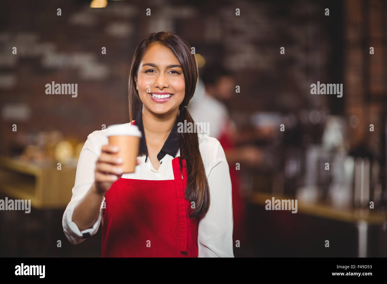 Lächelnde Kellnerin Übergabe einen Take-away-Becher Stockfoto