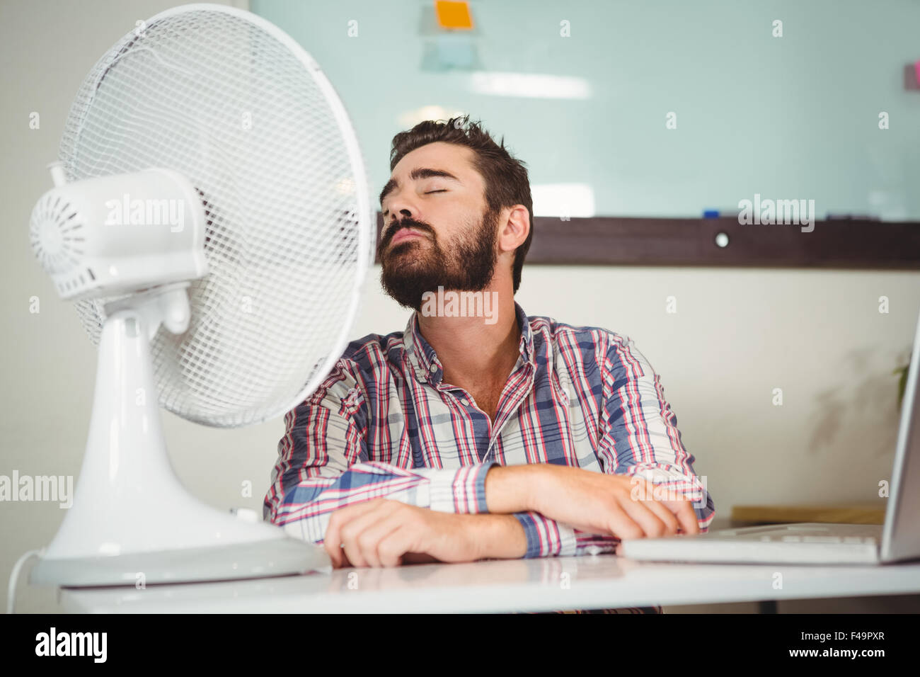 Geschäftsmann, sitzen auf Stuhl vor elektrischer Ventilator Stockfoto