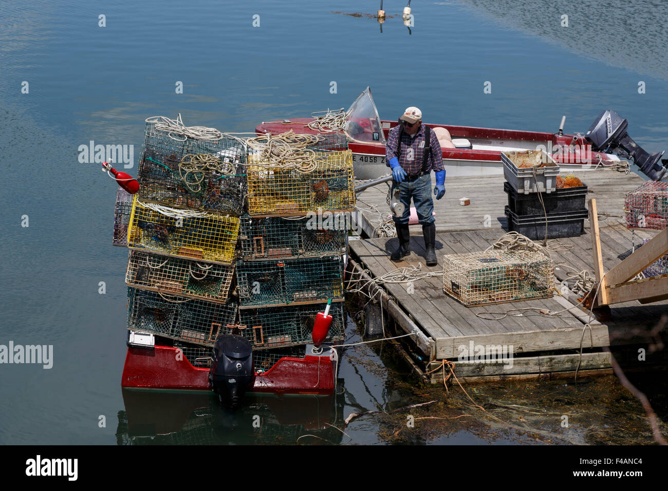 Fischer laden Hummer Töpfe auf kleinen Boot von einem schwimmenden hölzerne dock Harpswell Sound Maine USA Stockfoto