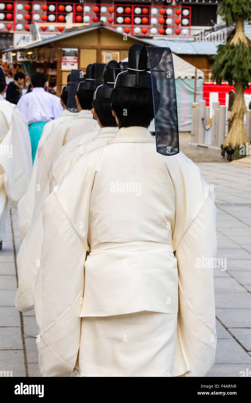 Nishinomiya Schrein, Japan, Shinto Priester Zeremonie, Priester, kannushi, Fuß in der Linie, alle tragen Kammuri, schwarze Hüte. Ansicht von hinten. Stockfoto