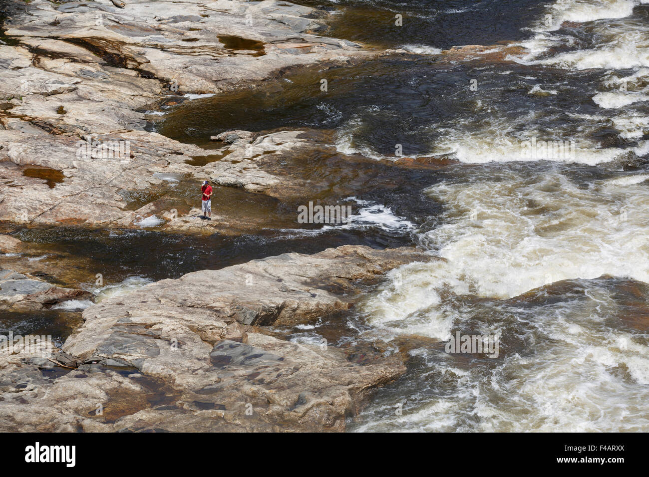 Mann in Shorts und t-Shirt Angeln in den stürmischen Gewässern des Androscoggin River gesehen von Portland Straßenbrücke Stockfoto