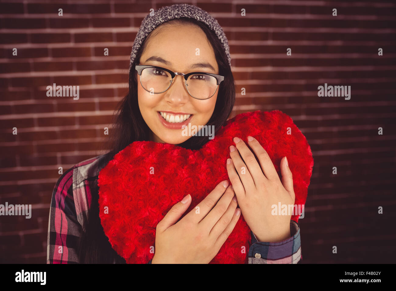 Attraktive junge Frau hält herzförmige Kissen Stockfoto