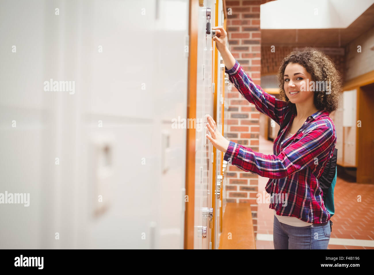 Hübsche Studentin ihr Schließfach zu öffnen Stockfoto