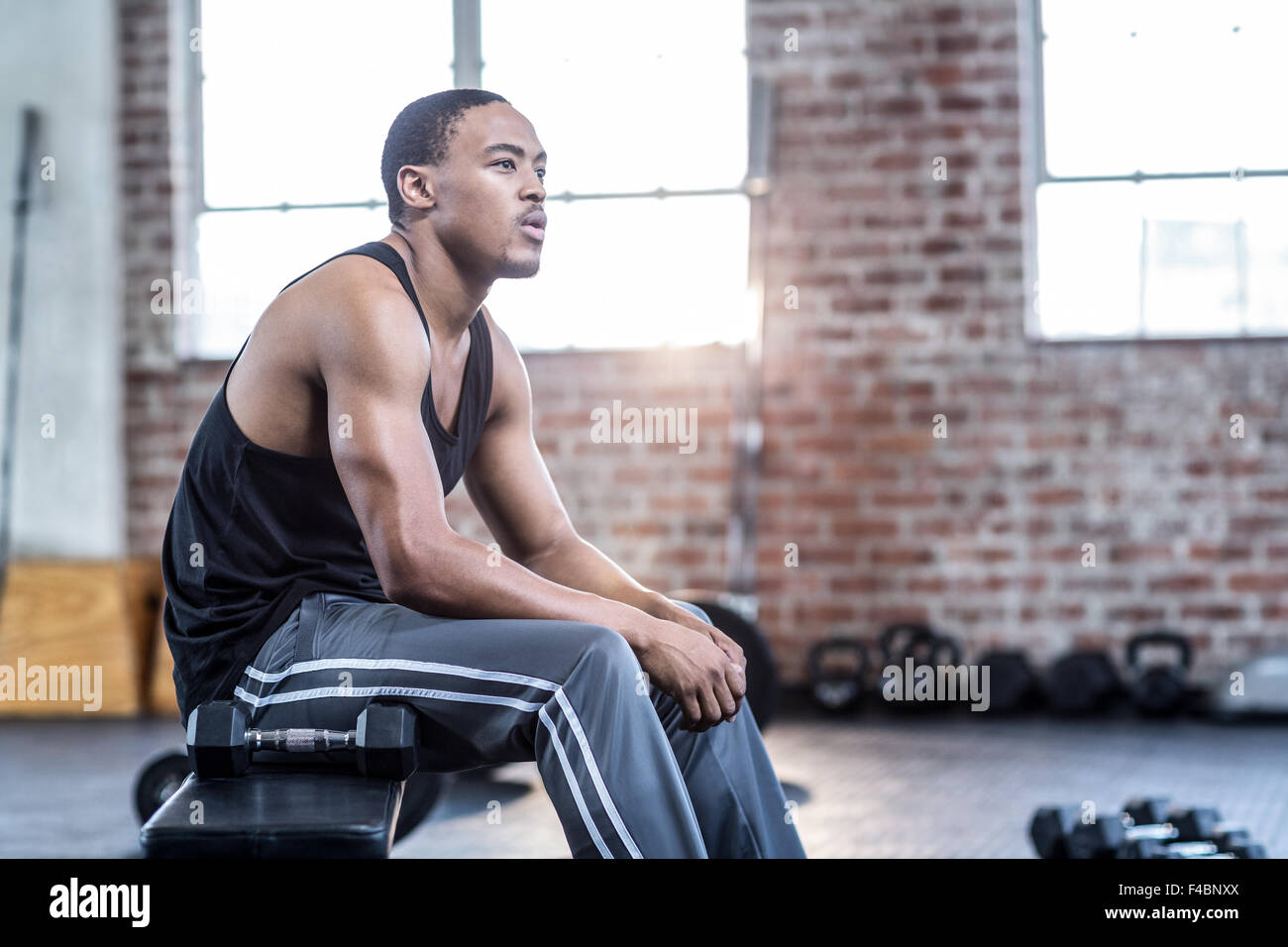 Muskulöser Mann sitzt auf einer Bank-Training Stockfoto