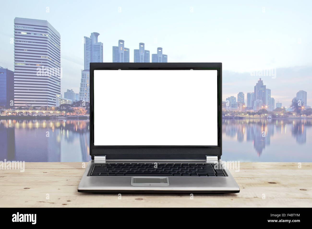 Laptop mit leeren Bildschirm auf Holztisch mit hohen Gebäude Hintergrund Stadtbild Konzept Geschäftsidee Stockfoto