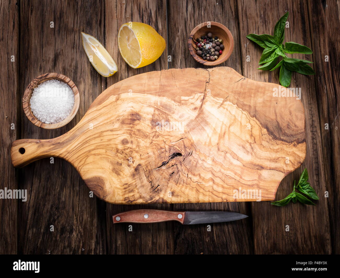 Olive-Schneidebrett und Gewürze auf einem Holztisch. Stockfoto