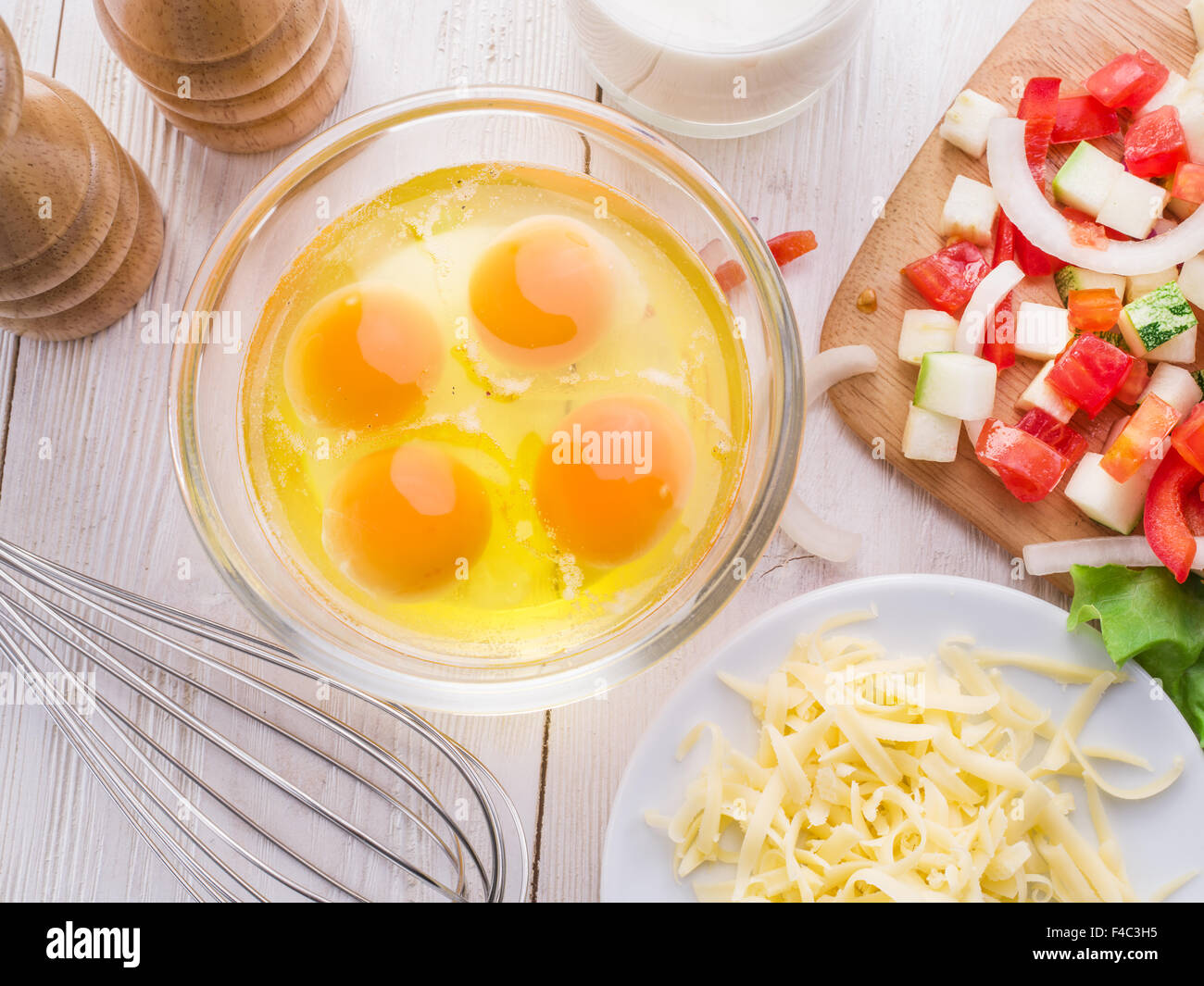 Omelette-Zutaten: Eiern, frisch geschnittene Gemüse, Milch und Käse auf dem Holztisch Stockfoto