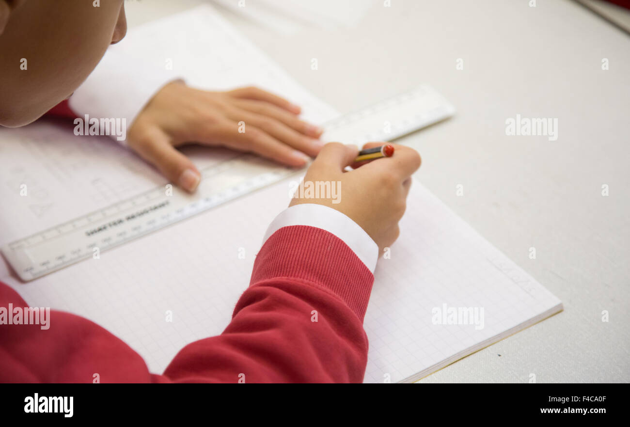 Ein typisches UK Grundschule Klassenzimmer mit einer Schülerin eine Linie mit einem Lineal zeichnen Stockfoto