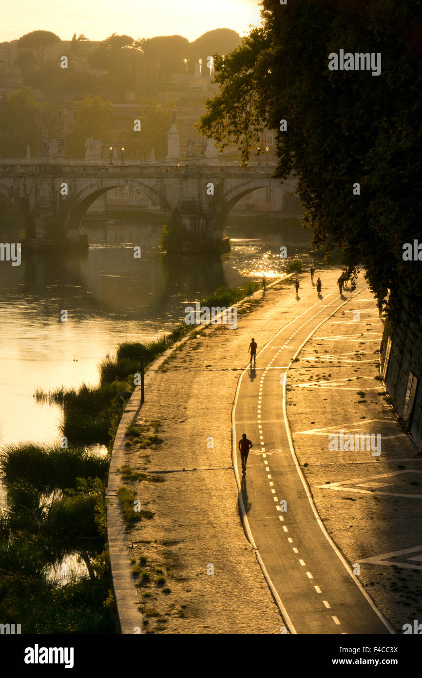 Wanderweg entlang der Seite des Flusses Tiber bei Wanderern und Joggern einfahren am späten Nachmittag und die Sant'Angelo Brücke, Rom, Italien Stockfoto