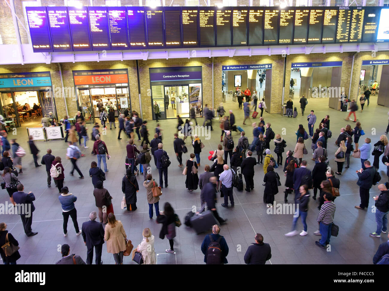 Passagiere sehen Anzeigentafel in Kings Cross Bahnhof, London Stockfoto