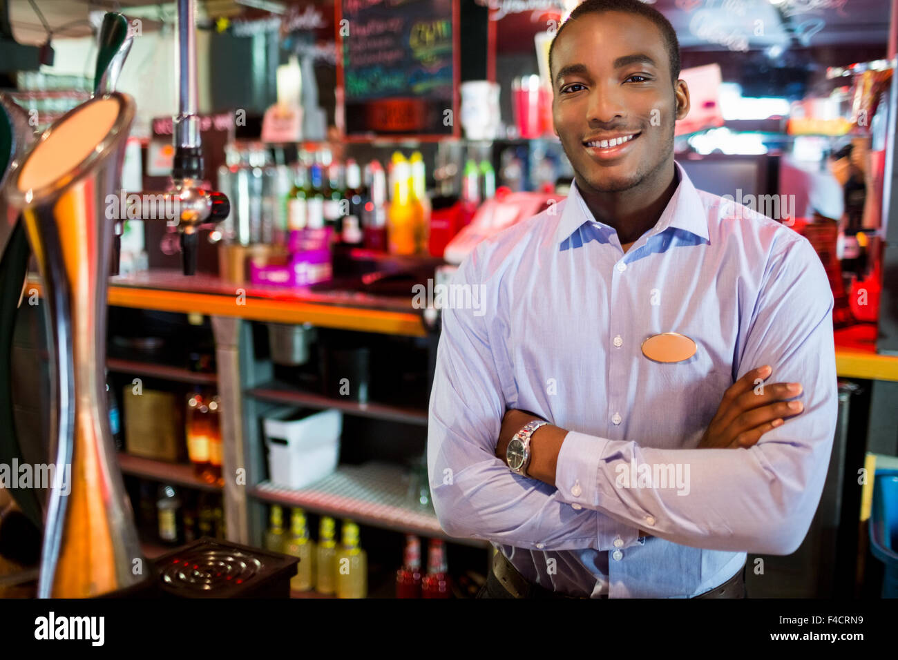 Barkeeper in der Nähe von Hahn posiert lächelnd Stockfoto