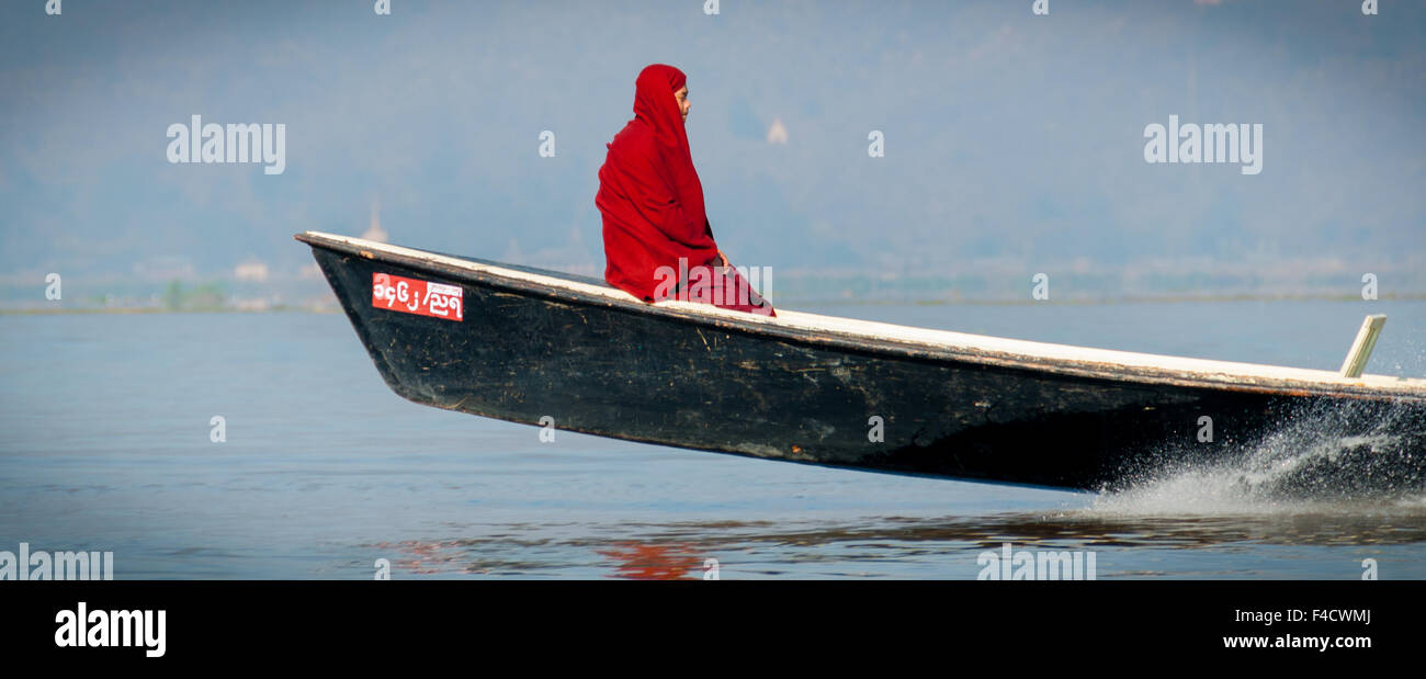 Mönch im roten Gewand sitzt auf einem Motorboot Stockfoto