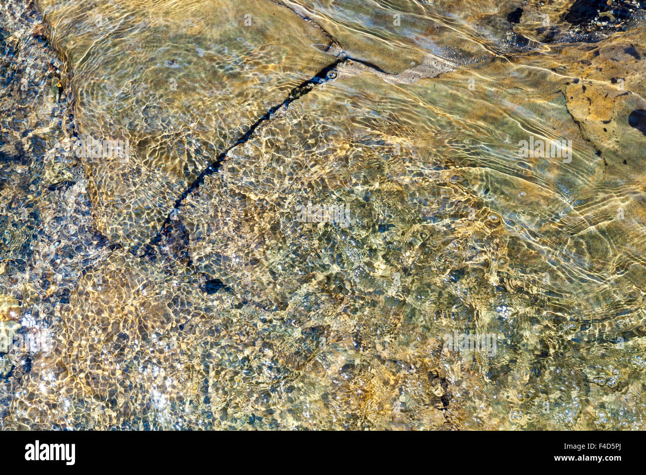 Abstrakte detail, von oben gesehen, der ein Strom fließt über Felsen und kleinen Steinchen, wodurch das Wasser Welligkeit und ein Muster erstellen. England, Großbritannien Stockfoto