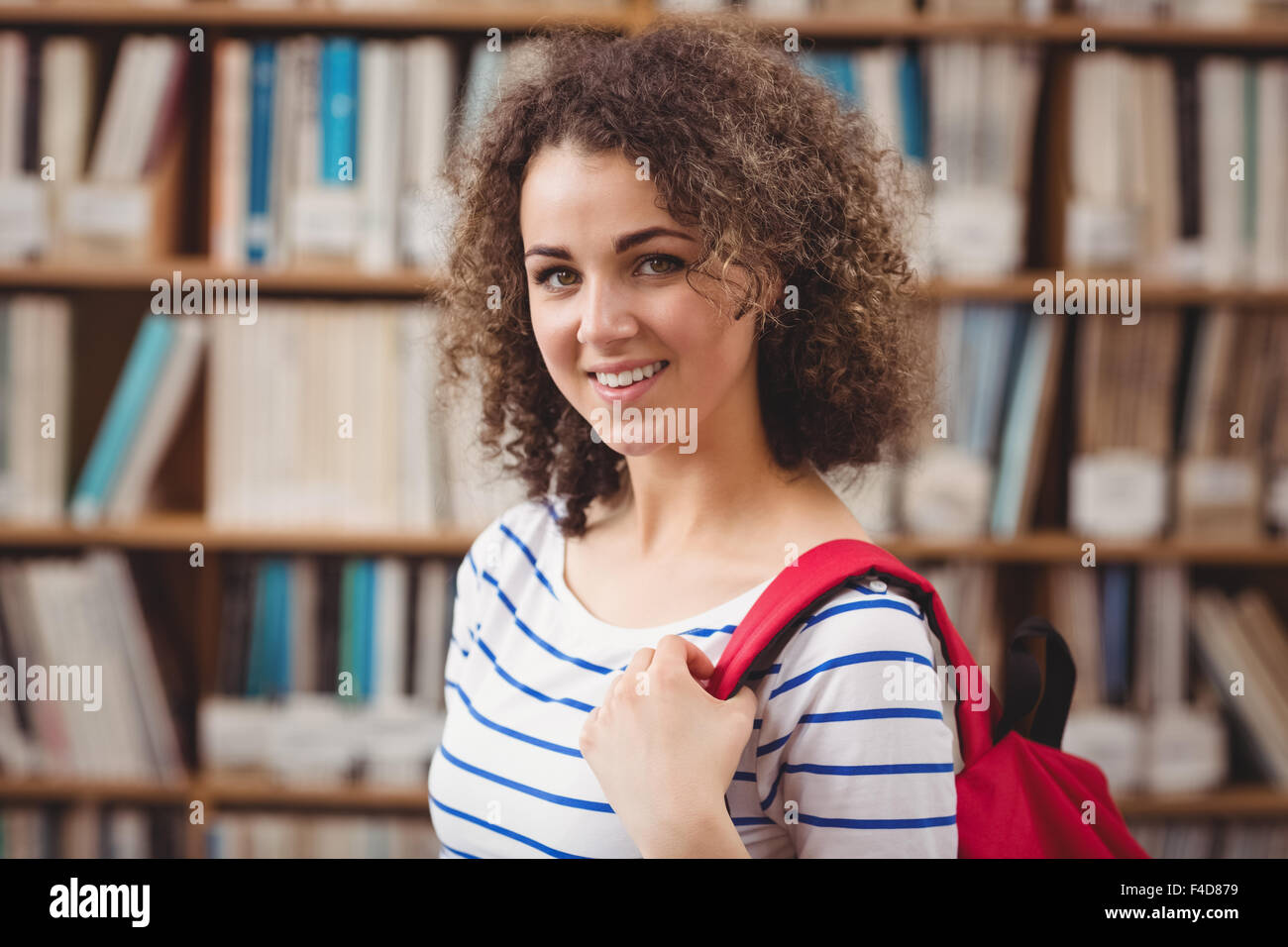 Hübsche Studentin in der Bibliothek in die Kamera Lächeln Stockfoto