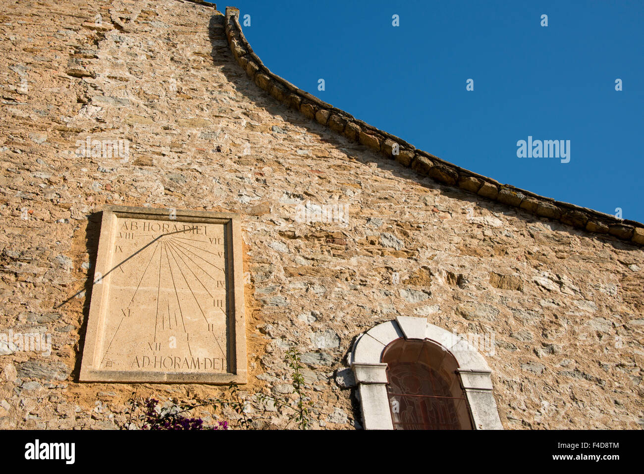 Frankreich, Provence, Bormes-Les-Mimosas. Saint-Trophyme Kirche, gebaut im 18. Jahrhundert in romanischem Stil. Steinmauer mit Sonnenuhr. (Großformatige Größen erhältlich) Stockfoto