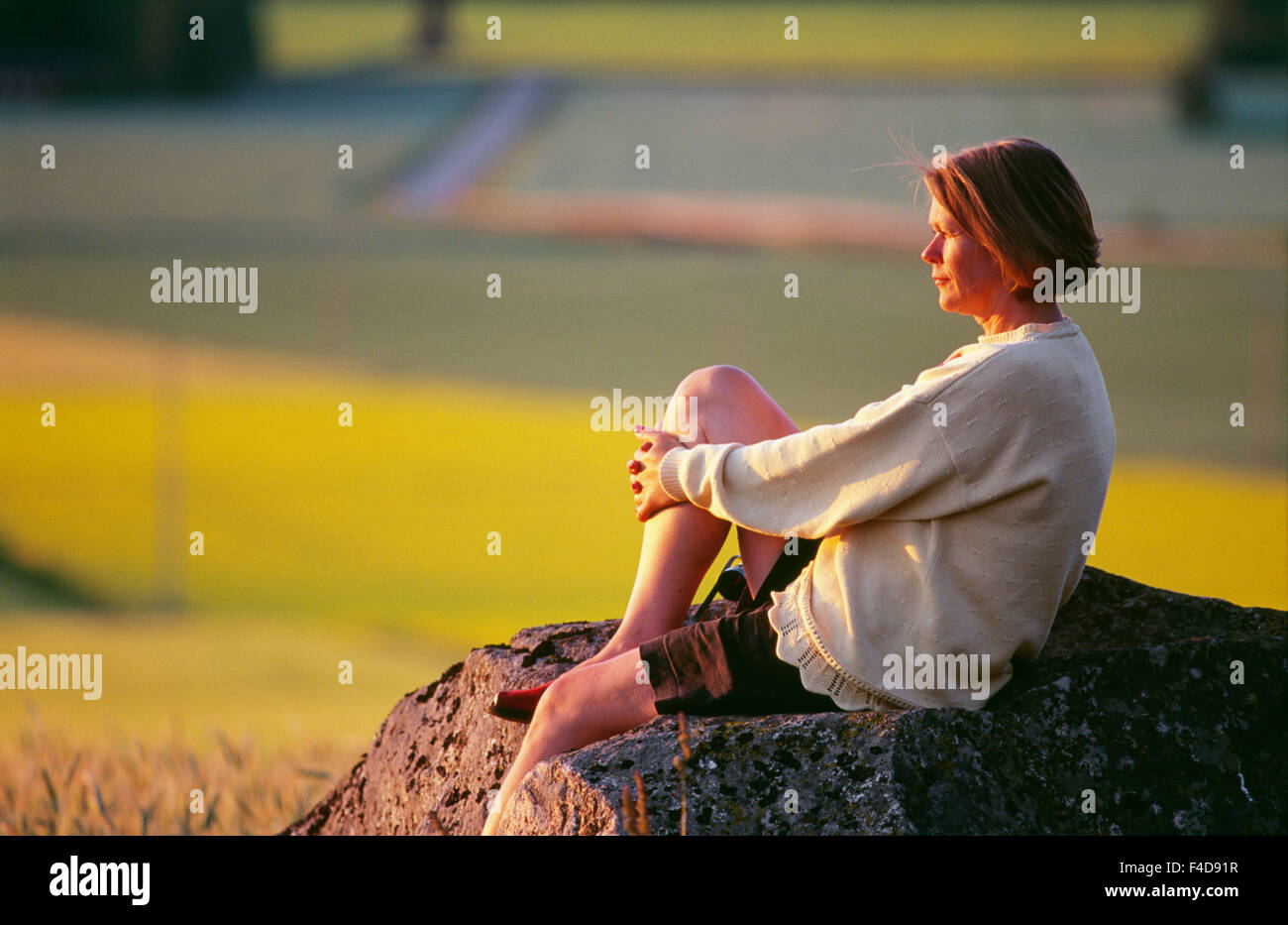 Mitte Erwachsene Frau sitzt auf Felsen, Seitenansicht Stockfoto