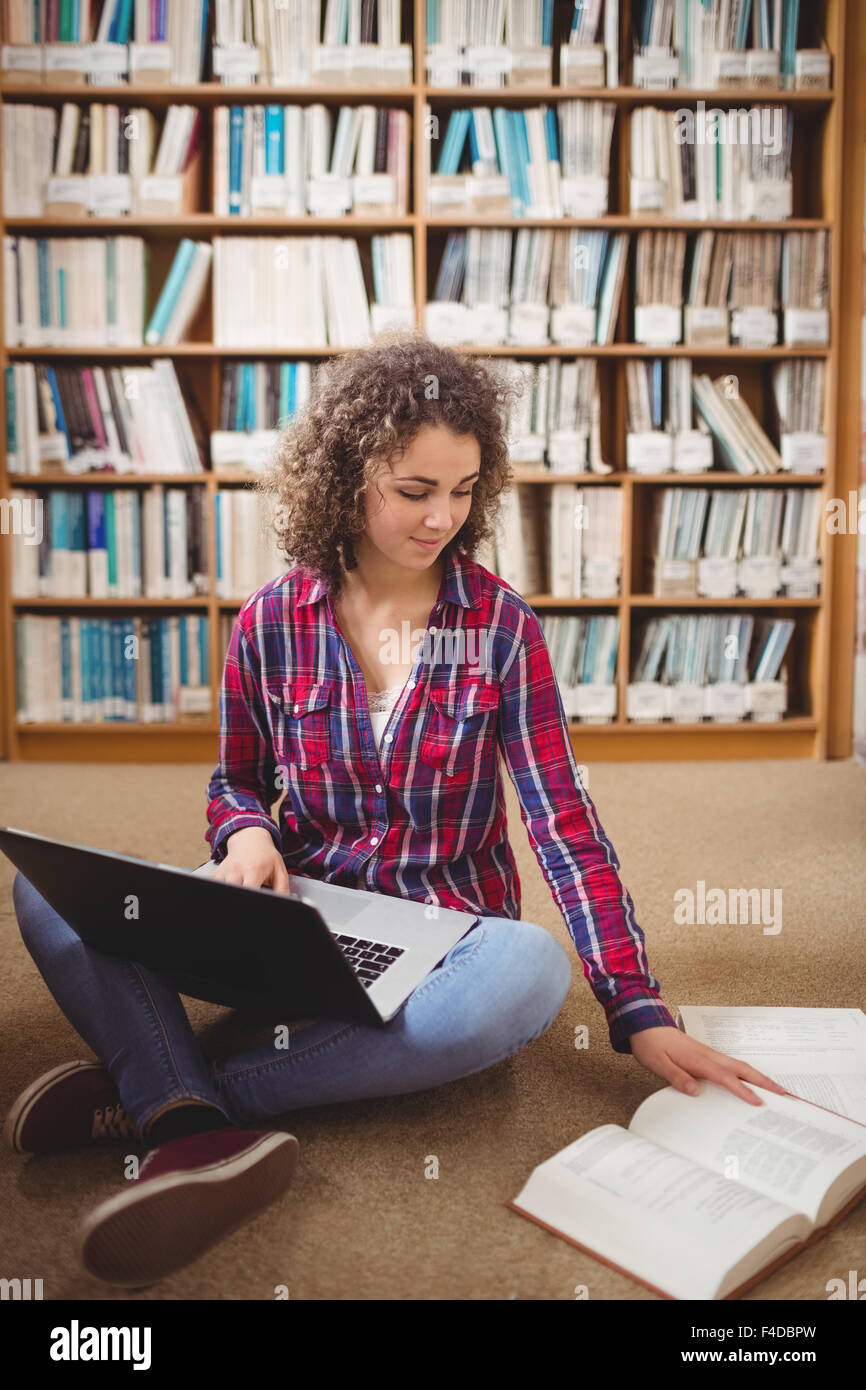 Hübsche Studentin in der Bibliothek mit laptop Stockfoto