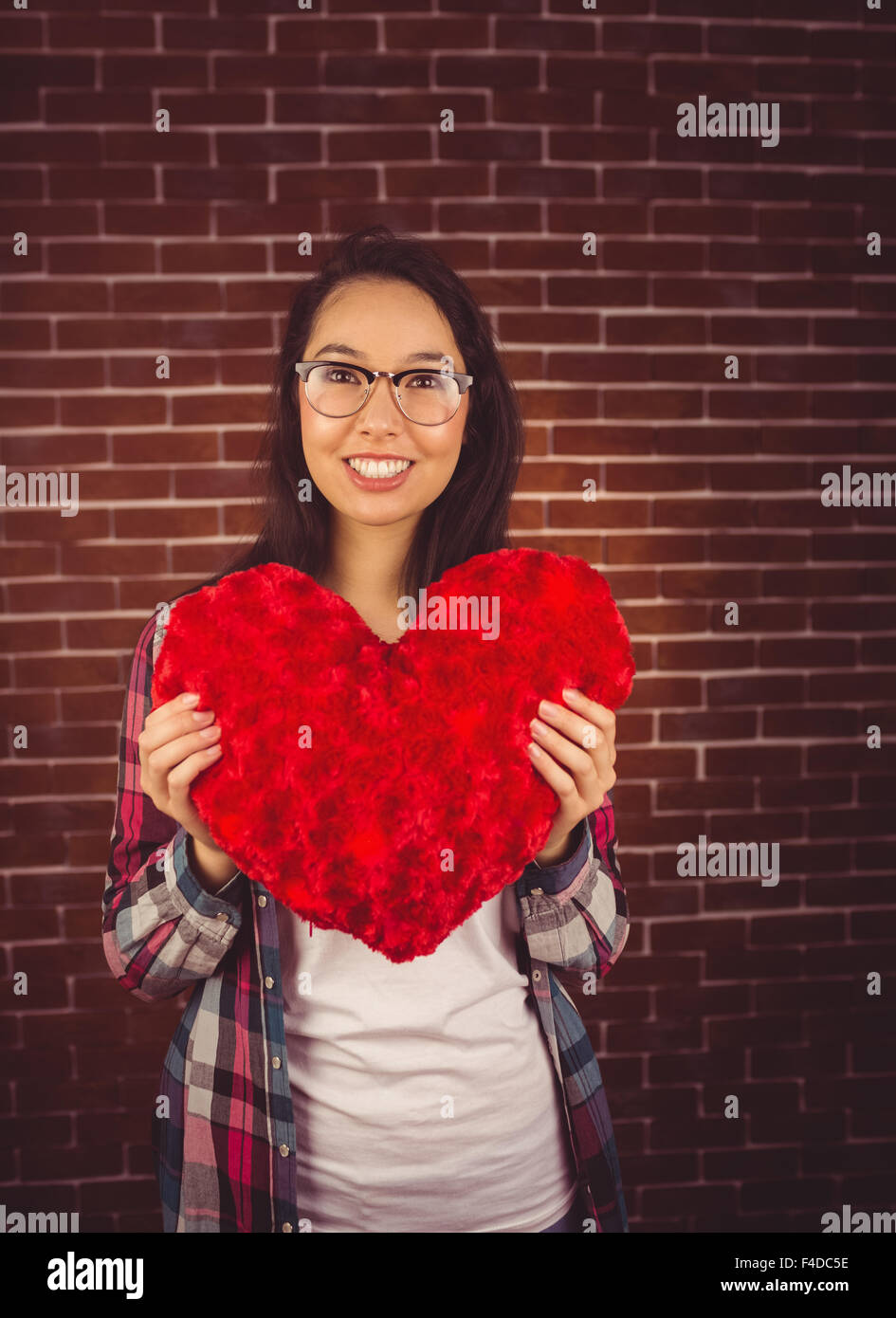 Attraktive junge Frau hält herzförmige Kissen Stockfoto