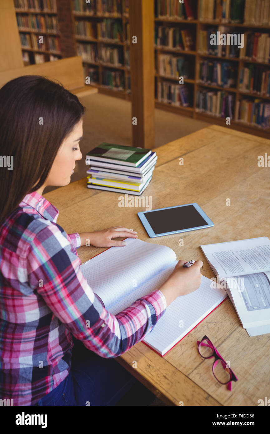 Studentin in Buch am Tisch schreiben konzentriert Stockfoto