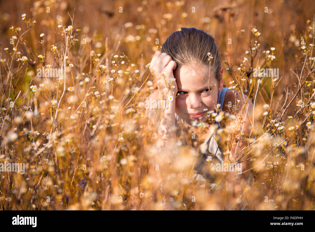 Schöne, 11 Jahre altes Mädchen im Feld sitzen zwischen Blumen Stockfoto