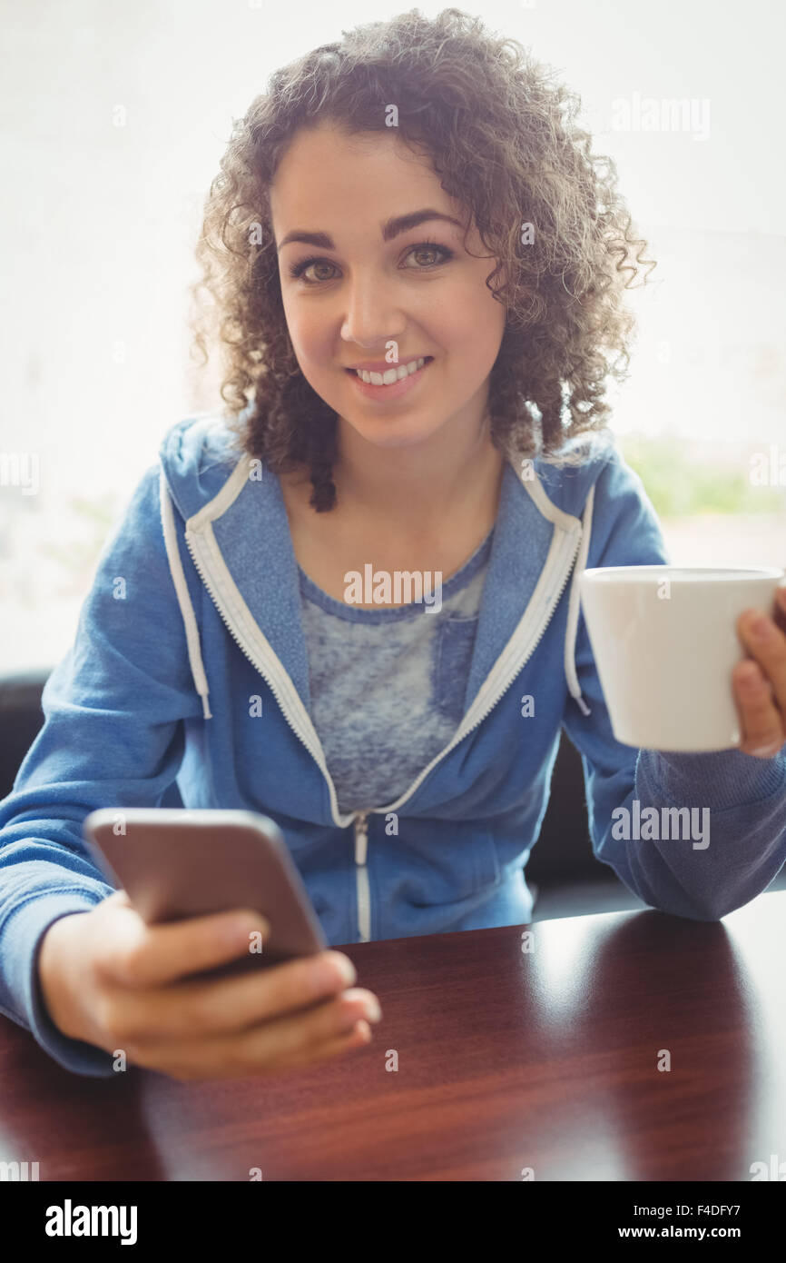 Hübsche Studentin mit ihrem Telefon im café Stockfoto