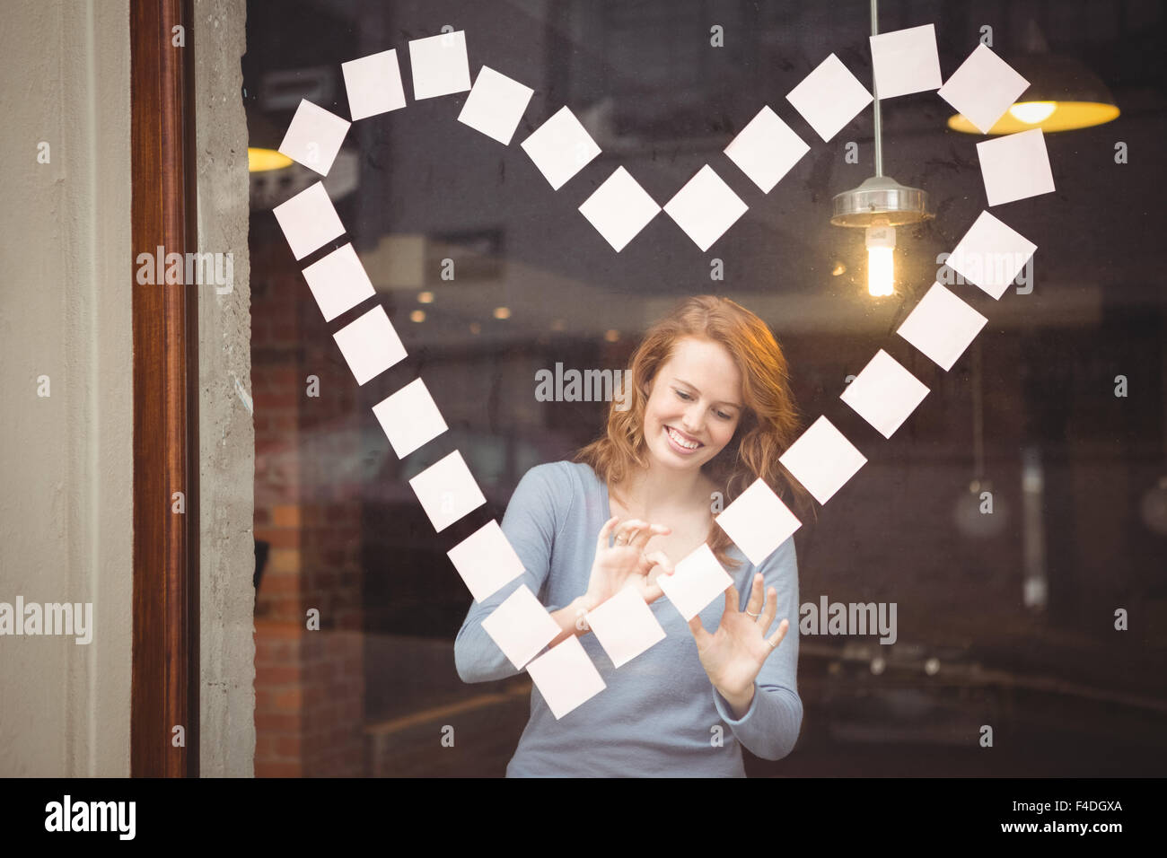 Glückliche Frau kleben Klebefuge Notizen in Herzform Stockfoto
