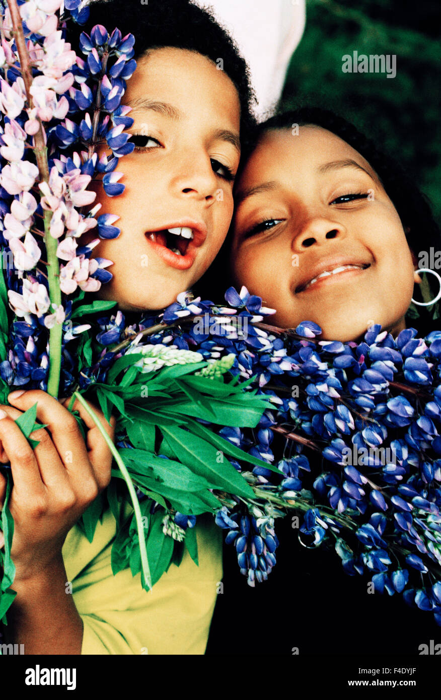 Ein Mädchen, 7 Jahre alt, und ein Junge, 8 Jahre alt, mit Blumen. Stockfoto