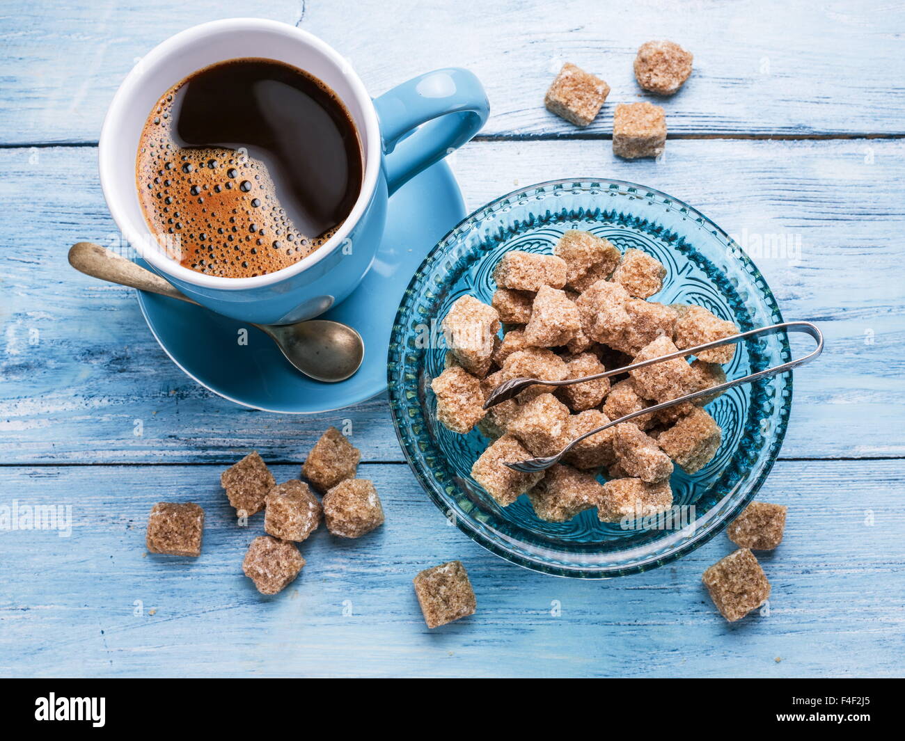 Tasse Kaffee und Rohrzucker Würfel auf alten blauen Holztisch. Stockfoto