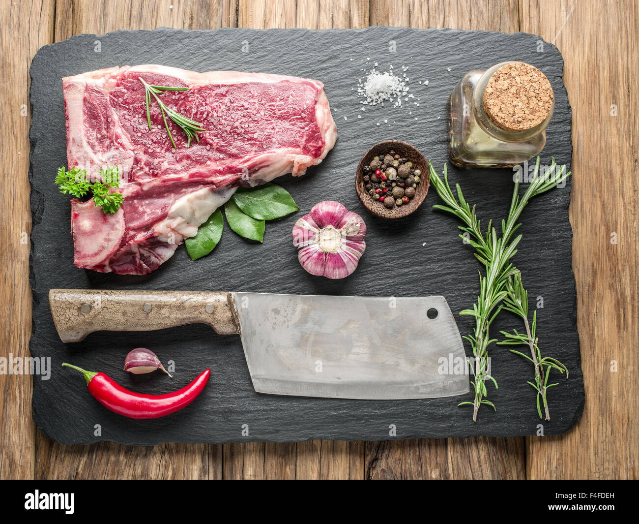 Rohes Fleisch Steaks mit Gewürzen auf dem schwarzen Schneidebrett. Stockfoto