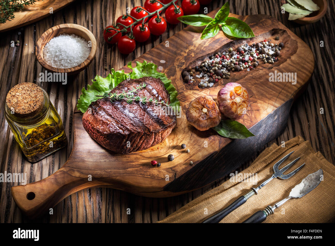 Rindersteaks mit Gewürzen auf einem Holztablett. Gegrillte Speisen. Stockfoto