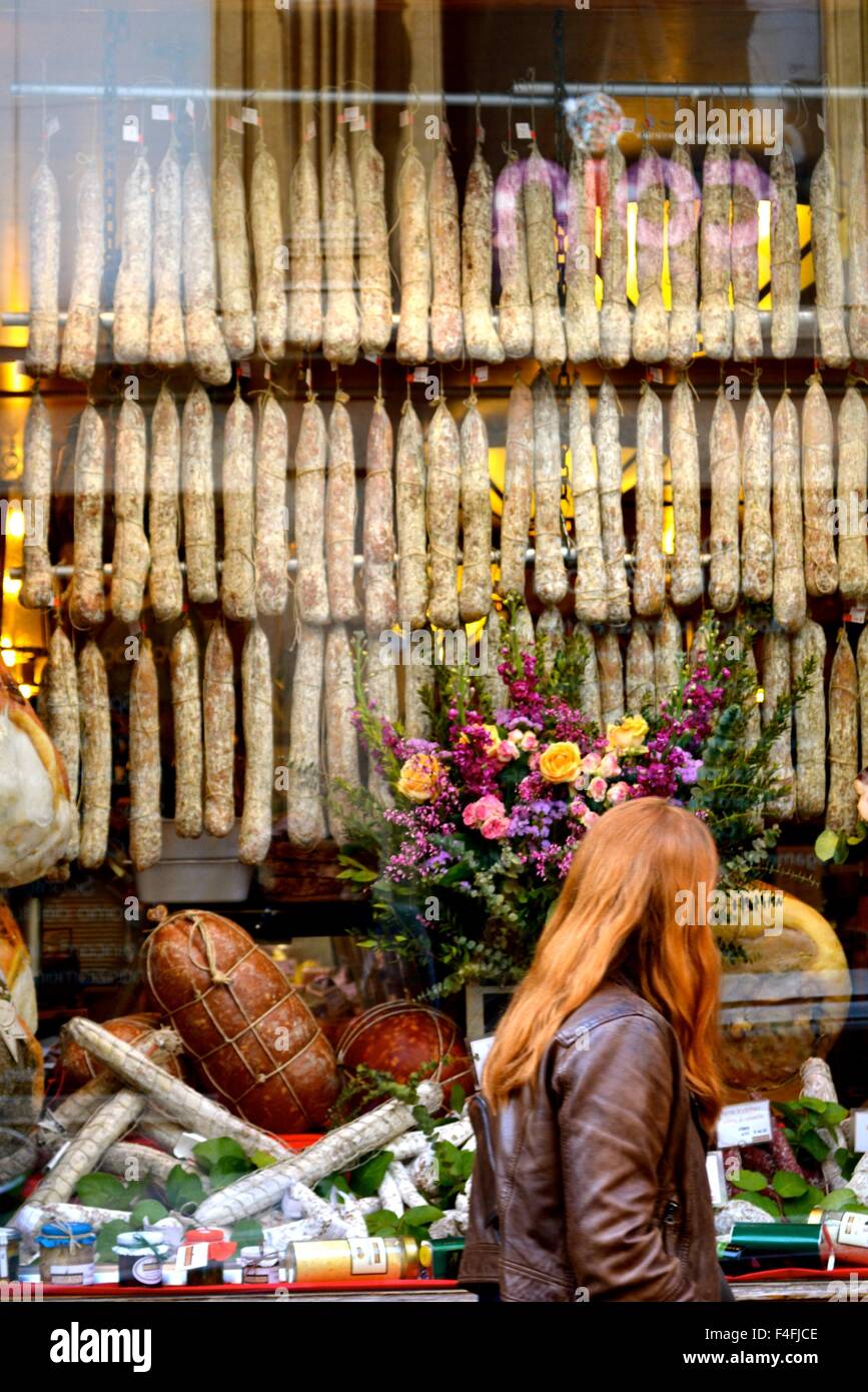 Frau, die in einem Fenster ein Geschäft mit Salami in Bologna Italien Stockfoto