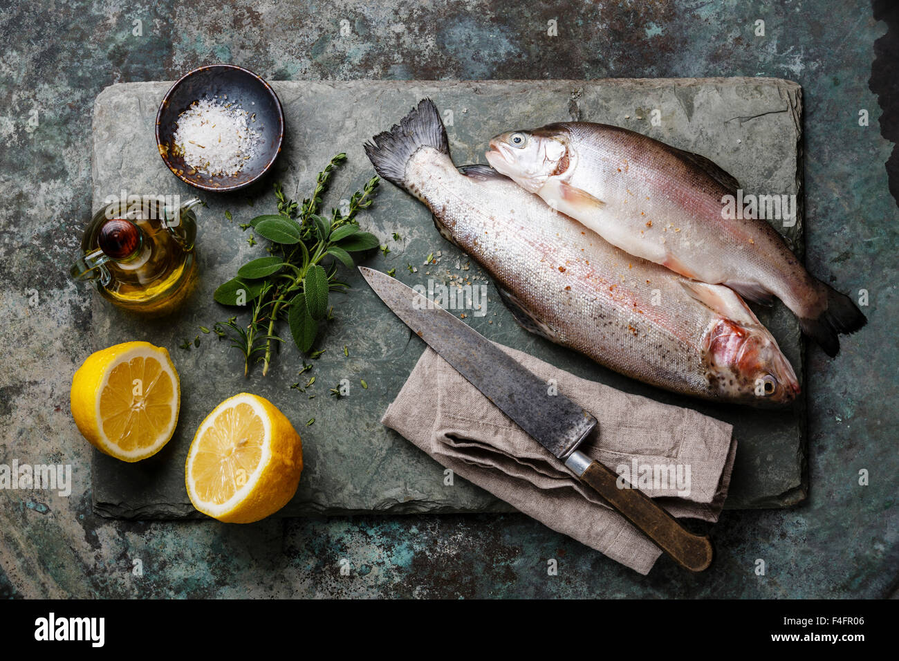 Rohe ungekochte Forellen mit Gewürzen und Kräutern auf Schiefer Stockfoto