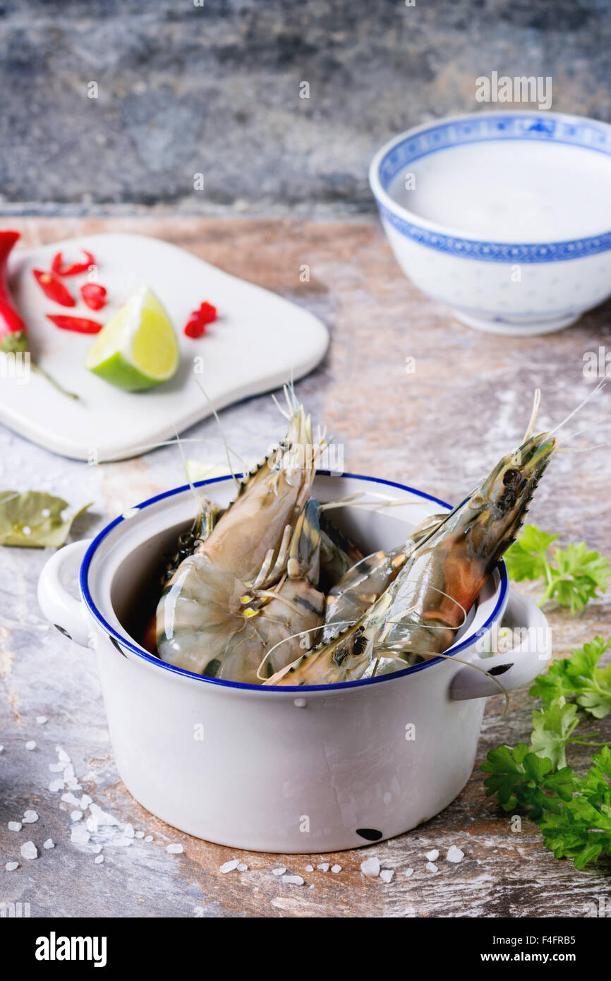 Zutaten für würzige Thai Suppe Tom Yam Kokosmilch, Chili Peppers, Shiitake Pilzen und Garnelen in Keramikschalen über Stein Stockfoto