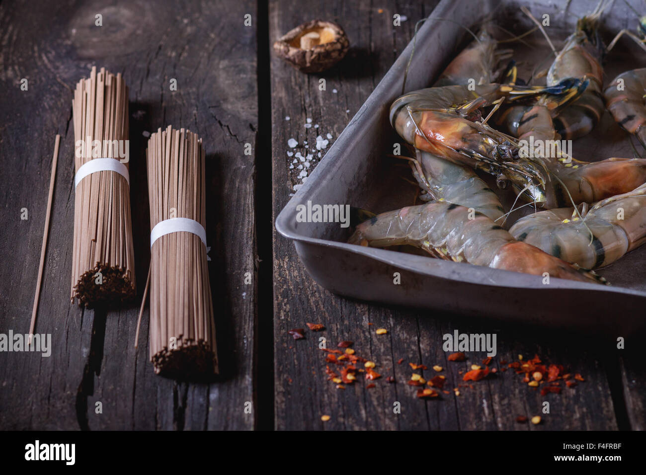 Zutaten für asiatische Abendessen ungekocht Soba-Nudeln, eingeweichten Shiitake-Pilzen und Garnelen über alten hölzernen Hintergrund mit Salz ein Stockfoto