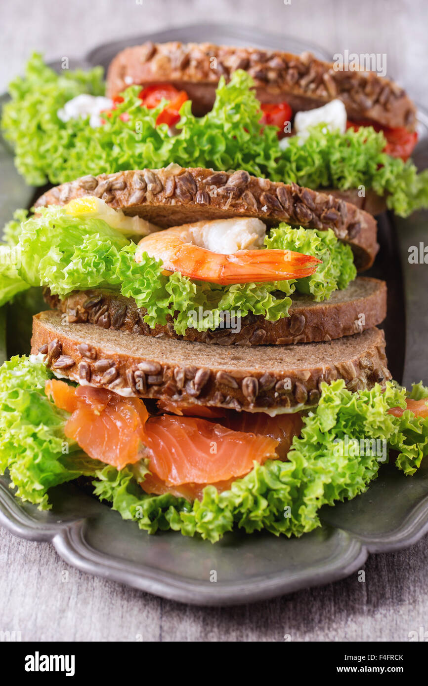 Satz von Sandwiches mit Vollkornbrot, frischem Salat, Feta-Käse, Cherry-Tomaten, Garnelen und gesalzener Lachs auf Vintage Metall p Stockfoto