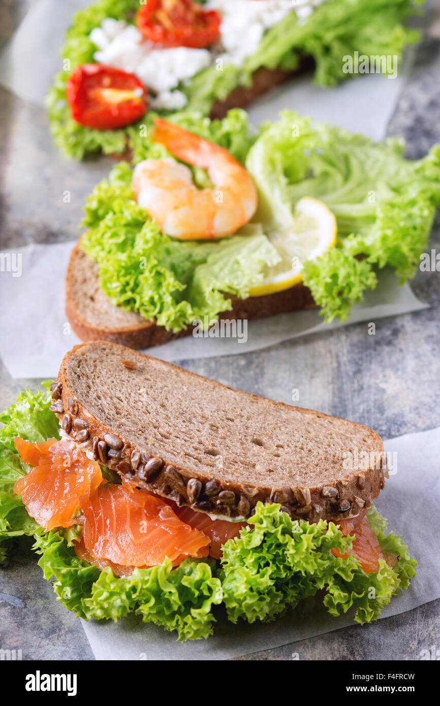 Satz von Sandwiches mit Vollkornbrot, frischem Salat, Feta-Käse, Cherry-Tomaten, Garnelen und gesalzener Lachs auf alte Zinn Hinterg Stockfoto