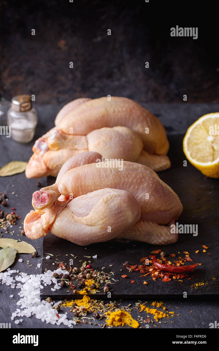 Zwei Raw Mini Huhn mit Meer-Salz und verschiedenen Gewürzen über Schiefer Tafel Stockfoto