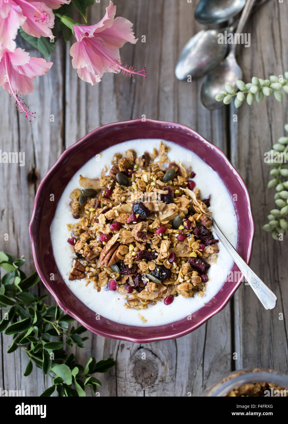 Eine Schüssel mit würzigen Kürbis, Ahorn und Tahini Müsli ist auf einem Bauernhof-Stil-Brett mit frisch gepflückten Blumen angezeigt. Stockfoto