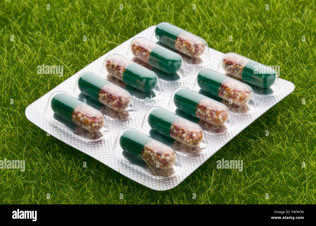 Grüne Pillen in einem Blister Paket auf grünen Rasen Hintergrund Stockfoto