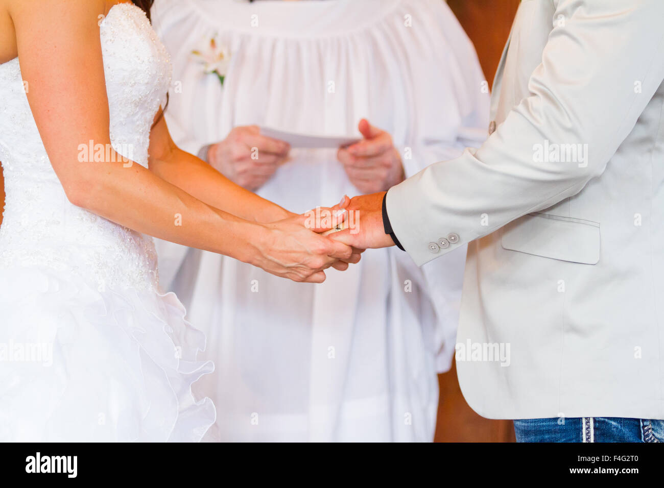 Braut und Bräutigam, Hände halten, während das Ja-wort am Tag ihrer Hochzeit in einer Scheune. Stockfoto