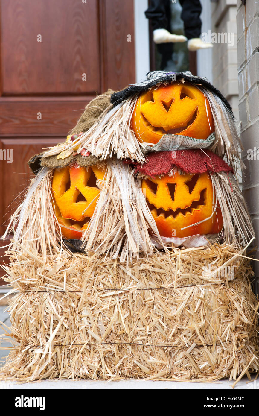 Künstliche Kürbisse auf Heu schmücken eine Veranda an Halloween. Stockfoto