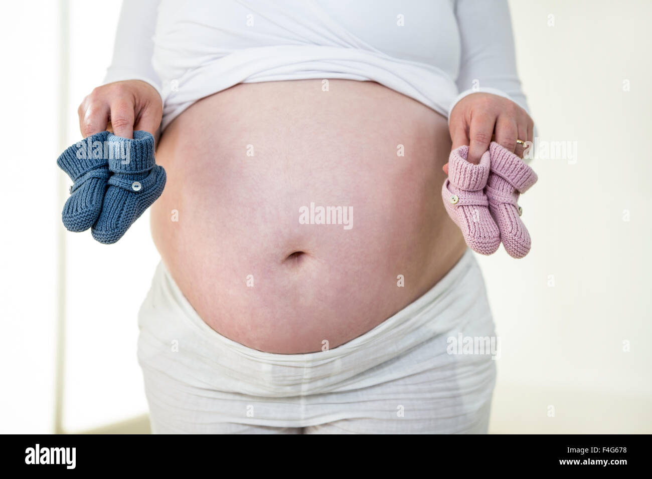 Schwangere Frau mit Babysocken Stockfoto